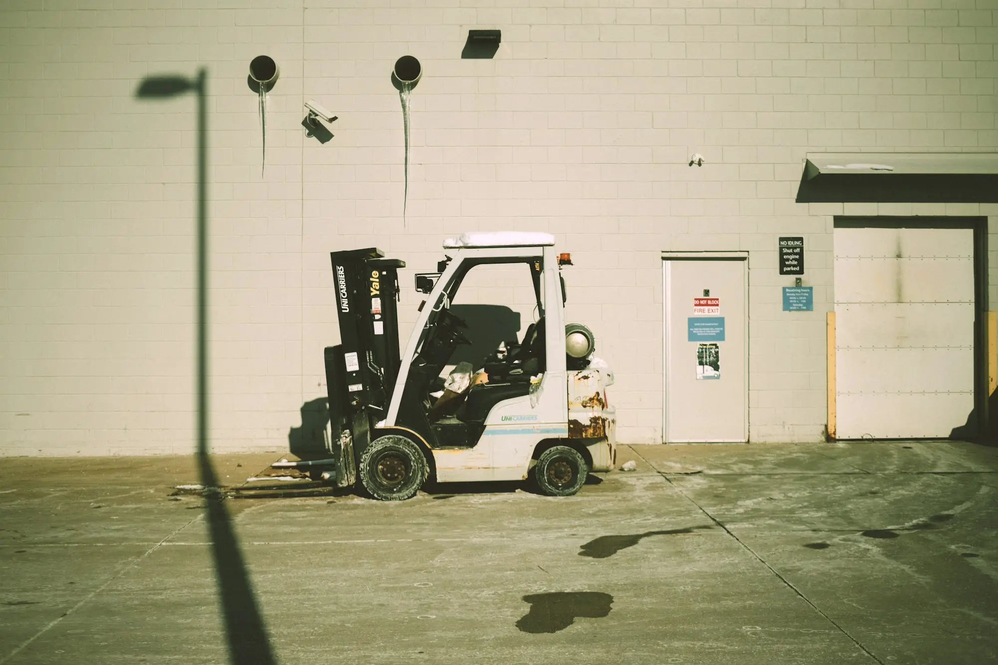 Forklift parked outside a warehouse building, a common equipment purchase